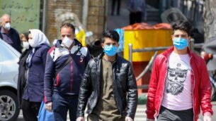 إيرانيون يرتدون أقنعة واقية ضد فيروس كورونا أثناء سيرهم في أحد شوارع العاصمة طهران، 5 أبريل 2020 (ATTA KENARE / AFP)