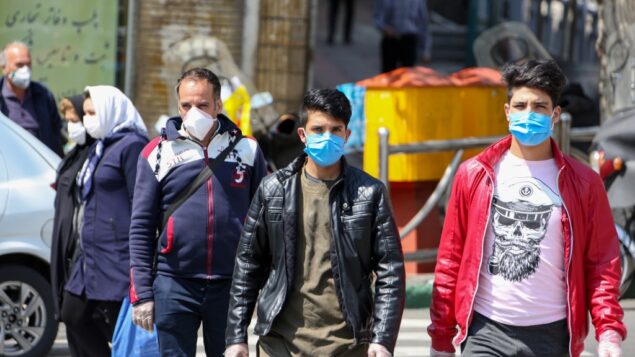 إيرانيون يرتدون أقنعة واقية ضد فيروس كورونا أثناء سيرهم في أحد شوارع العاصمة طهران، 5 أبريل 2020 (ATTA KENARE / AFP)