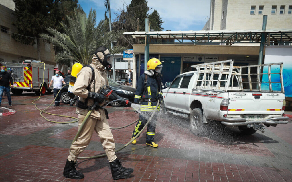 عمال بلدية فلسطينيون يقومون بتعقيم موقف سيارات في أحد مستشفيات مدينة رام الله بالضفة الغربية، 12 مارس، 2020. (Flash90) عمال بلدية فلسطينيون يقومون بتعقيم موقف سيارات في أحد مستشفيات مدينة رام الله بالضفة الغربية، 12 مارس، 2020. (Flash90)