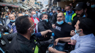 اعتقلت الشرطة رجلاً خلال احتجاج أصحاب الأكشاك في سوق محاني يهودا بالقدس على الإغلاق المستمر لمتاجرهم، 26 أبريل 2020 (Yonatan Sindel / Flash90)