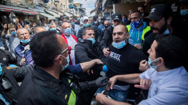اعتقلت الشرطة رجلاً خلال احتجاج أصحاب الأكشاك في سوق محاني يهودا بالقدس على الإغلاق المستمر لمتاجرهم، 26 أبريل 2020 (Yonatan Sindel / Flash90)