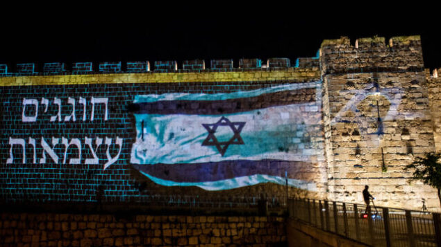 العلم الإسرائيلي على جدران المدينة القديمة بالقدس، بينما تحتفل إسرائيل بيوم استقلالها الثاني والسبعين تحت الإغلاق بسبب فيروس كورونا، 28 أبريل 2020. (Yonatan Sindel / Flash90)