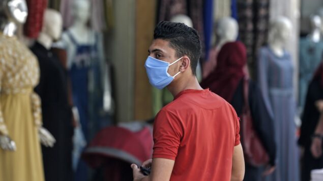 شاب فلسطيني يرتدي قناعا يعود من صلاة الجمعة الأخيرة في شهر رمضان، في مدينة غزة، 22 مايو 2020 (MAHMUD HAMS / AFP)