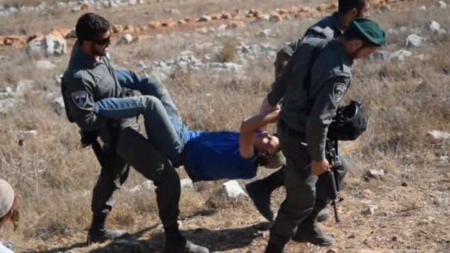 صورة توضيحية: عناصر شرطة الحدود يحملون أحد عناصر ’شبان التلال’ أثناء إخلاء بؤرة استيطانية غير قانونية في شمال الضفة الغربية. (Zman Emet, Kan 11)