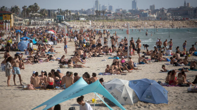 في تحد لقيود فيروس كورونا، يستمتع الإسرائيليون بالشاطئ في تل أبيب، بينما ارتفعت درجات الحرارة إلى 40 درجة مئوية في بعض أنحاء البلاد، 16 مايو 2020. (Miriam Alster / Flash90)