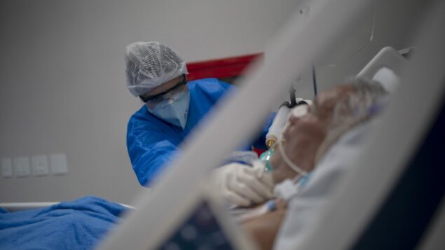 أخصائي صحي يقدم الرعاية لمريض في جناح وحدة العناية المركزة (ICU) حيث يتم علاج المرضى المصابين بفيروس كورونا الجديد في مستشفى دكتور إرنستو تشي جيفارا العام في مدينة ماريكا، ولاية ريو دي جانيرو، البرازيل، 5 يونيو 2020. (Mauro Pimentel / AFP)