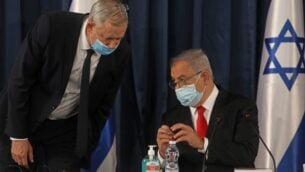 رئيس الوزراء بنيامين نتنياهو (يمين) يتحدث مع رئيس الوزراء البديل ووزير الدفاع بيني غانتس، وكلاهما يرتديان اقنعة وقائية بسبب جائحة كوفيد-19، خلال الاجتماع الأسبوعي للحكومة في القدس، 7 يونيو 2020. (Menahem KAHANA / AFP)