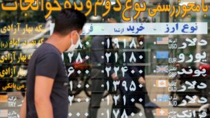 رجل يرتدي قناعًا بسبب فيروس كورونا يتحقق من أسعار صرف العملات وهو يمشي في العاصمة الإيرانية طهران، 22 يونيو 2020 (ATTA KENARE / AFP)