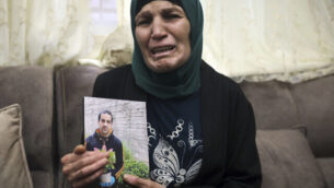 رنا الحلاق، والدة إياد الحلاق (32 عاما)، تحمل صورته في منزلها في وادي الجوز بالقدس الشرقية، 30 مايو، 2020. (AP Photo/Mahmoud Illean)