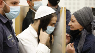 عميرام بن أوليئل (يسار)، الذي أدين بتنفيذ هجوم دوما، يصل إلى جلسة استماع في المحكمة المركزية في اللد،  9  يونيو، 2020. (Tomer Appelbaum/Haaretz/Pool)