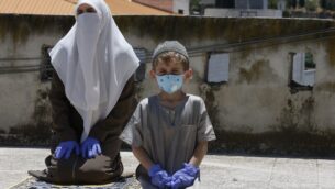 أفراد عائلة إمام في مسجد محلي يؤدون صلاة الجمعة على سطح منزلهم، بعد أن أغلقت السلطة الفلسطينية المساجد بسبب وباء فيروس كورونا في مدينة الخليل بالضفة الغربية، 3 يوليو 2020 (Hazem Bader/AFP)