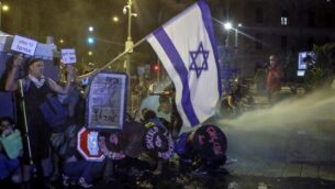 المتظاهرون يجلسون على الأرض بينما تستخدم الشرطة خراطيم المياه ضدهم في القدس، 25 يوليو 2020. (AHMAD GHARABLI / AFP)