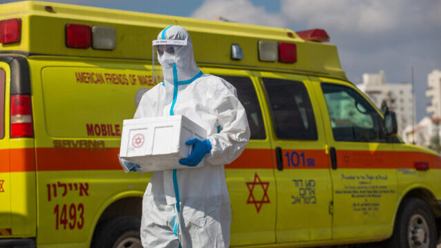 أحد العاملين في نجمة داوود الحمراء يجري فحوصات لإسرائيليين في محطة ’افحص وسافر’ لجمع عينات لتشخيص فيروس كورونا في اللد، 10 يوليو، 2020. (Yossi Aloni/Flash90)