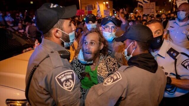 الشرطة تعتقل رجلا خلال لال ظاهرة ضد رئيس الوزراء بنيامين نتنياهو أمام مقر إقامته الرسمي في القدس، فجر الأربعاء، 22 يوليو، 2020.  (Yonatan Sindel/Flash90)