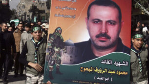 فلسطينيون يحملون صورة محمود المبحوح بينما يحمل آخرون نعشه، يسار، خلال جنازته في مخيم اليرموك، بالقرب من دمشق، سوريا، 29 يناير 2010 (AP Photo / Bassem Tellawi / File)