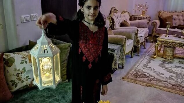 طفلة أفراد عائلة أبو صبيح بالقدس تحمل رفع فانوس في غرفة المعيشة في صورة لها قبل هدم منزل العائلة. (إياد أب صبيح)