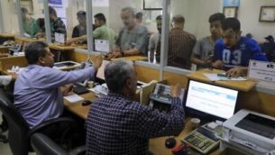 فلسطينيون يتلقون مساعدات مالية من قطر في مكتب بريد في مدينة غزة، 27 يونيو، 2020. (Mahmud Hams / AFP)