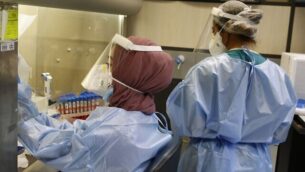 عاملتا مختبر تختبران عينات من أشخاص يُشتبه بأنهم مرضى Covid-19 في مختبر علم الفيروسات السريري في مستشفى هداسا عين كارم في القدس، 30 سبتمبر، 2020.  (GIL COHEN-MAGEN / AFP)