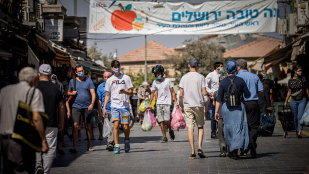 أشخاص يرتدون أقنعة الوجه يتسوقون في سوق محانيه يهودا في القدس، خلال إغلاق في جميع أنحاء البلاد لمنع انتشار كوفيد-19، 7 أكتوبر 2020 (Yonatan Sindel / Flash90) أشخاص يرتدون أقنعة الوجه يتسوقون في سوق محانيه يهودا في القدس، خلال إغلاق في جميع أنحاء البلاد لمنع انتشار كوفيد-19، 7 أكتوبر 2020 (Yonatan Sindel / Flash90)