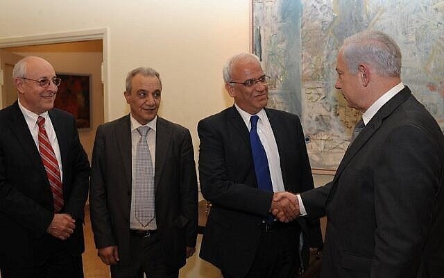 رئيس الوزراء بنيامين نتنياهو يصافح صائب عريقات في القدس، أبريل 2012. مساعد نتنياهو يتسحاق مولخو على اليسار، ورئيس جهاز الأمن في السلطة الفلسطينية ماجد فرج، الثاني من اليسار. (Amos Ben Gershom /GPO/Flash90)