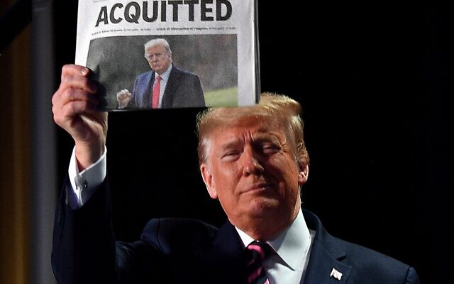 صورة ملف التقطت في 6 فبراير 2020، يرفع فيها الرئيس الأمريكي دونالد ترامب صحيفة تحمل عنوان "براءة"، في واشنطن العاصمة (Nicholas Kamm / AFP)