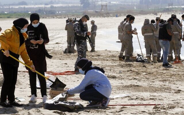 متطوعون من جمعيات شبابية ينظفون شاطئًا ملوثًا في مدينة صور جنوب لبنان، بعد تسرب نفطي أغرق الساحل الشمالي لإسرائيل ووصل إلى أجزاء من الشواطئ اللبنانية المجاورة، 27 فبراير 2021 (Mahmoud ZAYYAT / AFP)