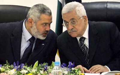 رئيس السلطة الفلسطينية محمود عباس، من اليمين، ورئيس وزراء السلطة الفلسطينية آنذاك إسماعيل هنية، من اليسار، يتحدثان أثناء ترأسهما الاجتماع الوزاري الأول للحكومة الائتلافية الجديدة في مكتب عباس في مدينة غزة، 18 مارس، 2007.  (AP Photo/Khalil Hamra, File)