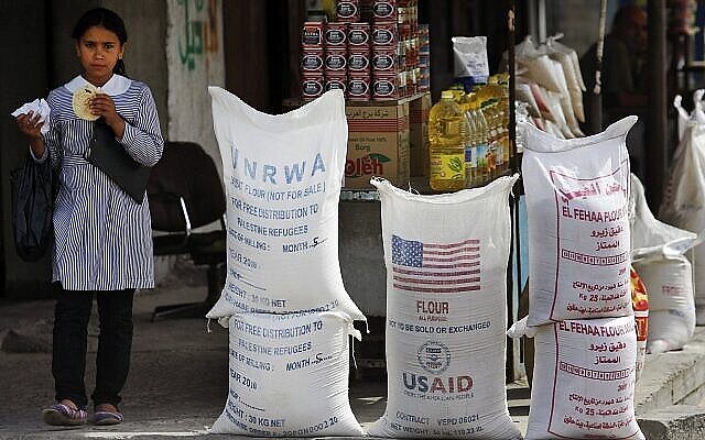 تلميذة فلسطينية تمر بجانب مساعدات إنسانية من وكالة الأمم المتحدة لإغاثة وتشغيل اللاجئين (الأونروا) والوكالة الأمريكية للتنمية الدولية، في 6 يونيو، 2010، في مخيم الشاطئ في مدينة غزة. (AP Photo/Lefteris Pitarakis, File)