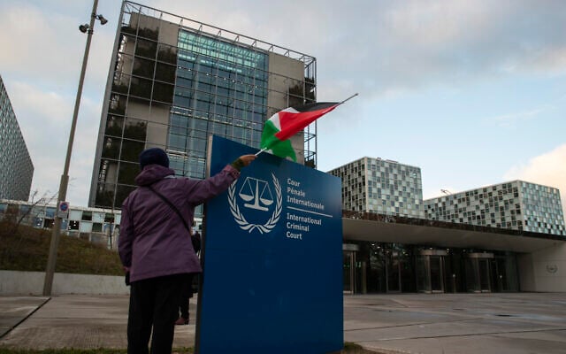 متظاهر يقف مع علم فلسطيني أمام المحكمة الجنائية الدولية، خلال تجمع للمطالبة بمحاكمة الجيش الإسرائيلي على ارتكاب جرائم حرب مزعومة، في لاهاي، هولندا، 29 نوفمبر 2019 (AP/Peter Dejong)