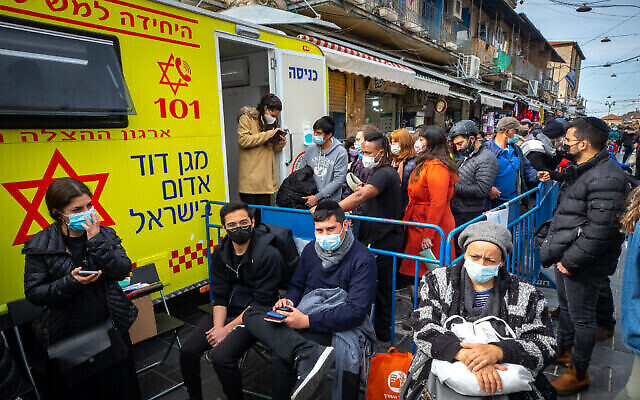 إسرائيليون يتلقون تطعيم كوفيد-19 في محطة متنقلة لنجمة داوود الحمراء في سوق محانيه يهودا في القدس، 22 فبراير، 2021. (Olivier Fitoussi / Flash90)