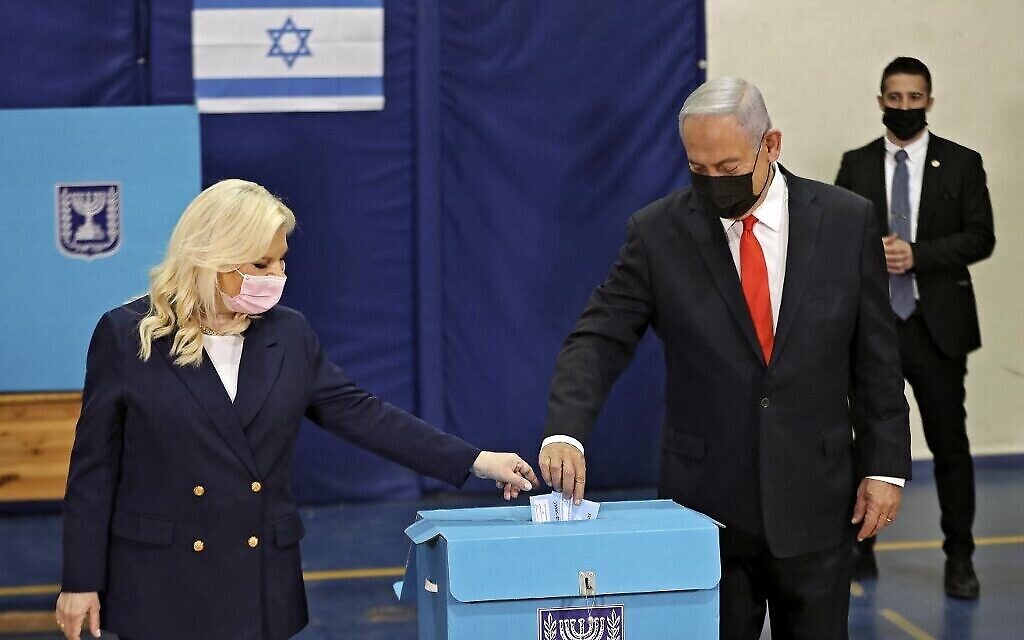 رئيس الوزراء بنيامين نتنياهو وزوجته سارة يدليان بأصواتهما في مركز اقتراع في القدس، في الانتخابات الوطنية الرابعة خلال عامين، 23 مارس 2021 (RONEN ZVULUN / POOL / AFP)
