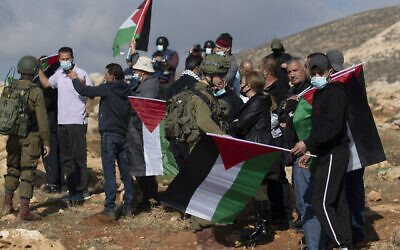جنود إسرائيليون يمنعون متظاهرين فلسطينيين من الوصول إلى بؤرة استيطانية يهودية في أطراف قرية المغير بالضفة الغربية، شمال رام الله، 18 ديسمبر، 2020. (AP / Nasser Nasser)