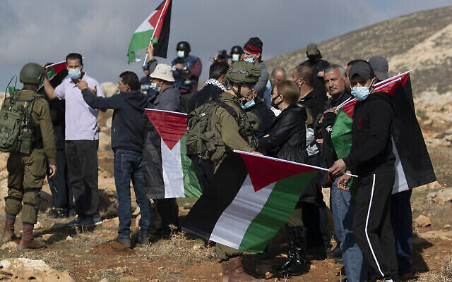 جنود إسرائيليون يمنعون متظاهرين فلسطينيين من الوصول إلى بؤرة استيطانية يهودية في أطراف قرية المغير بالضفة الغربية، شمال رام الله، 18 ديسمبر، 2020. (AP / Nasser Nasser)