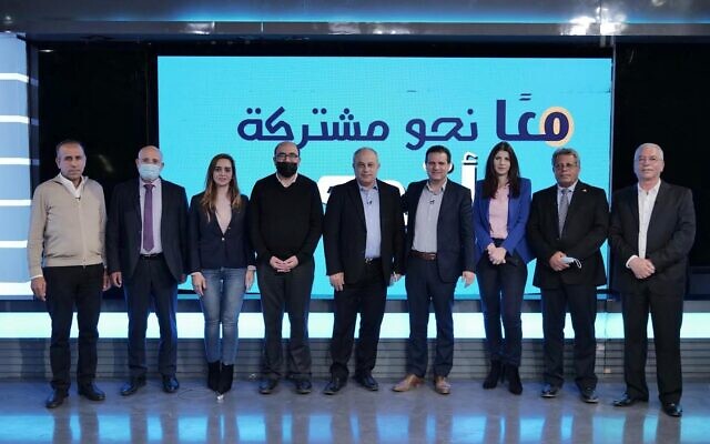 زعيم حزب "معا" أحمد دراوشة يقف وسط مجموعة من سياسيي "القائمة المشتركة" أمام شعار يعلن وحدة الأحزاب (Courtesy: Ma'an)