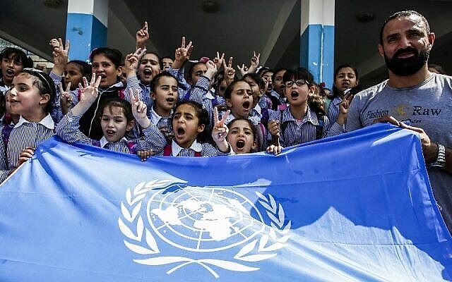 طلاب مدارس فلسطينيون يرددون شعارات ويرفعون إشارة النصر فوق علم الأمم المتحدة خلال احتجاج في مدرسة تابعة لوكالة الأمم المتحدة لإغاثة وتشغيل اللاجئين الفلسطينيين (الأونروا)، بتمويل من المعونات الأمريكية، في مخيم العروب للاجئين بالقرب من الخليل بالضفة الغربية في 5 سبتمبر ، 2018. (AFP PHOTO / HAZEM BADER)