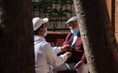 الناجي من المحرقة موطي ليبر  (88 عاما)، يتلقى الرعاية من متطوع في مقر مؤسسة "ياد عيزر لحافير" ، التي تدعم الناجين من المحرقة من خلال تزويدهم بالطعام بالإضافة إلى المساعدة الطبية والنفسية، في حيفا، 24 يناير، 2021, (Emmanuel DUNAND / AFP)