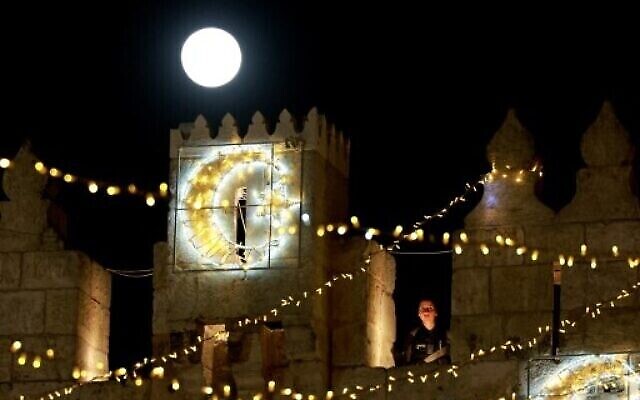 بدر شهر أبريل، المسمى "القمر الوردي الضخم"، يظهر فوق باب العامود بينما تقوم الشرطة الإسرائيلية بالحراسة في البلدة القديمة في القدس، 27 أبريل 2021 (Menahem KAHANA / AFP)