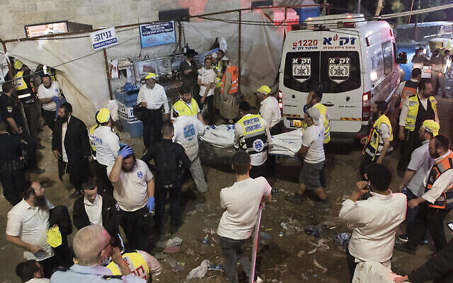 مسؤولون أمنيون وعمال إنقاذ إسرائيليون يحملون جثة أحد ضحايا التدافع خلال احتفالات لاغ باعمر في جبل ميرون في شمال إسرائيل، 30 أبريل، 2021. (AP Photo)