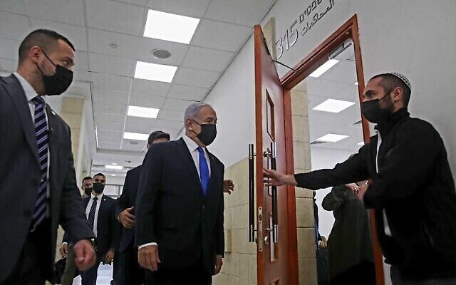 رئيس الوزراء بنيامين نتنياهو (وسط) يدخل قاعة محكمة القدس المركزية لجلسة استماع في محاكمته بالفساد، 5 أبريل 2021 (Oren Ben Hakoon / Pool)