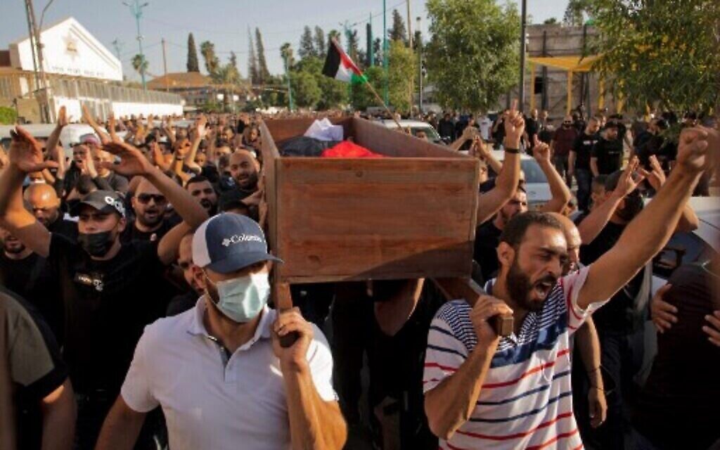 مواطنون عرب إسرائيليون يلوحون بالأعلام الفلسطينية أثناء تشييع جنازة موسى حسونة في مدينة اللد بوسط إسرائيل بالقرب من تل أبيب، في 11 مايو 2021. (AFP)
