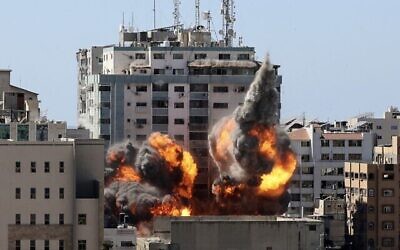 النار والدخان يتصاعدان من برج الجلاء بعد تدميره في غارة جوية إسرائيلية بعد أن حذر الجيش الإسرائيلي السكان وطالبهم بمغادرة المبنى، مدينة غزة، 15 مايو، 2021. (MAHMUD HAMS / AFP)