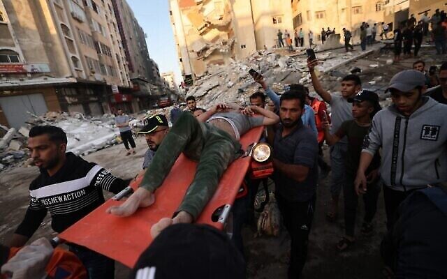 فلسطينيون يحملون أحد الناجين من تحت أنقاض أحد المباني بعد قصفه بغارات إسرائيلية في مدينة غزة، 16 مايو، 2021.