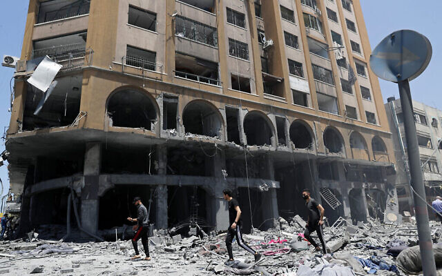 أشخاص يتفقدون أنقاض مبنى أصابته غارة جوية إسرائيلية بعد إطلاق صواريخ كثيف من القطاع، في مدينة غزة، 12 مايو 2021 (AP Photo / Adel Hana)