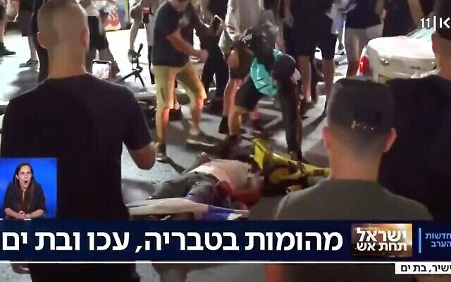 رجل يعتدي بالضرب على شخص ممدد على الأرض في مدينة بات يام الإسرائيلية وسط أعمال عنف عرقية في جميع أنحاء إسرائيل، 12 مايو، 2021. (Screenshot)