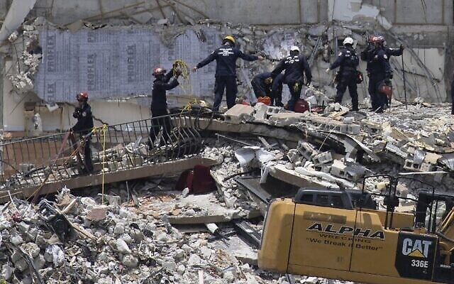فرق الإنقاذ تبحث عن ناجين محتملين في برج تشامبلين السكني المكون من 12 طابقا والذي انهار جزئيا في 26 يونيو 2021، في سيرفسايد، فلوريدا.  (JOE RAEDLE / GETTY IMAGES NORTH AMERICA / Getty Images via AFP)