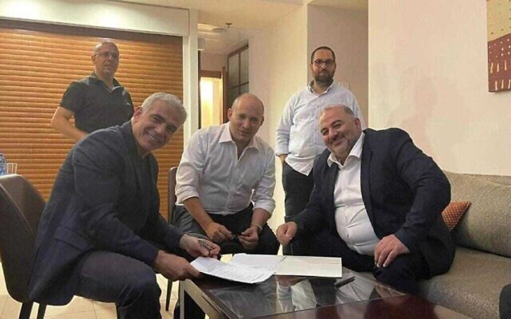 زعيم حزب يش عتيد، يائير لابيد (على يسار الصورة)، وزعيم يمينا، نفتالي بينيت (وسط الصورة)، وزعيم حزب التجمع منصور عباس يوقعون على اتفاق ائتلافي، 2 يونيو، 2021. (Courtesy of Ra’am)