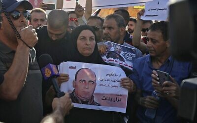 والدة الناشط السياسي الفلسطيني نزار بنات تحمل صورته خلال مسيرة في مدينة رام الله بالضفة الغربية  في 3 يوليو 2021 تندد بالسلطة الفلسطينية في أعقاب وفاة بنات أثناء احتجازه لدى قوات الأمن التابعة للسلطة الفلسطينية.  (ABBAS MOMANI / AFP)