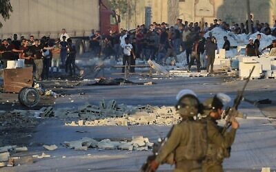 اشتباكات بين متظاهرين فلسطينيين والجنود الإسرائيليين يطالبون الجيش بتسليم جثة رجل قُتل برصاص القوات الإسرائيلية الليلة الماضية ، في قرية بيتا بالضفة الغربية، 28 يوليو، 2021.( by JAAFAR ASHTIYEH / AFP)
