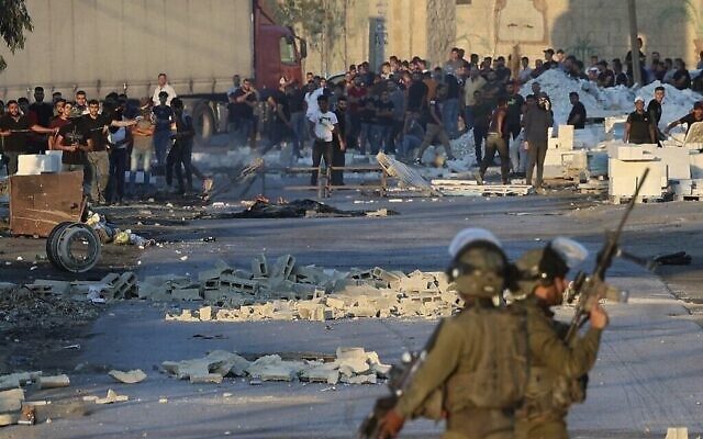 اشتباكات بين متظاهرين فلسطينيين والجنود الإسرائيليين يطالبون الجيش بتسليم جثة رجل قُتل برصاص القوات الإسرائيلية الليلة الماضية ، في قرية بيتا بالضفة الغربية، 28 يوليو، 2021.( by JAAFAR ASHTIYEH / AFP)