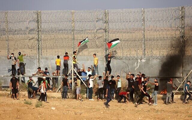 متظاهرون فلسطينيون يرفعون الأعلام الفلسطينية يحرقون الإطارات خلال مظاهرة عند السياج الحدودي مع إسرائيل ، شرقي مدينة غزة، 21 أغسطس، 2021. (Said Khatib / AFP)